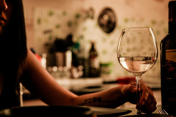White wine into the wineglass and female hand. Family celebration
