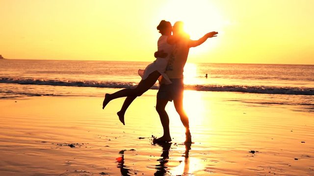 Happy couple turning round on beach during sunset, super slow motion 240fps
