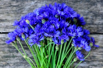 Fototapeta premium bouquet of wild flowers blue cornflowers on an old wooden table