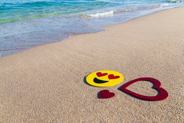 Happy smiley and hearts/Glitter heart eyes smiley sign and red glitter hearts on the tropical beach