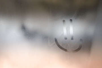 Smiley face painted on the window in foggy weather