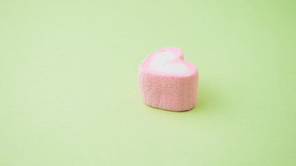 Pink heart-shaped marshmallow  on green background
