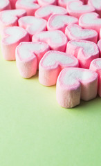 Pink heart-shaped marshmallow  on green background