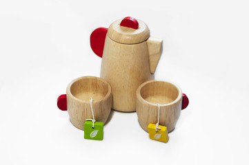 Still life of the wooden teapot and tow cups, isolated on white background. Wooden kids toys.