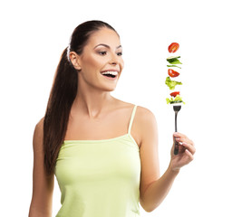 Beautiful, fit young woman holding a fork with vegetables