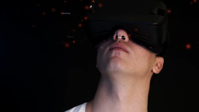 Smiling young man wearing VR Headset experiencing virtual reality. 3D objects flying around head.