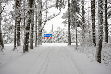 car tire tracks on winter road with road signs