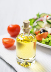 Bottle of olive oil with fresh vegetable Greek salad