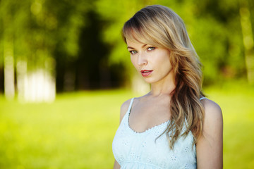 Naklejka premium Beautiful young blond woman outdoors. Sunny day. Nature summer background. Outside close-up portrait of beautiful young happy woman with fresh and clean skin