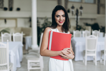 Restaurant manager. Beautifull business woman with folder restaurant menu and talk the phone.