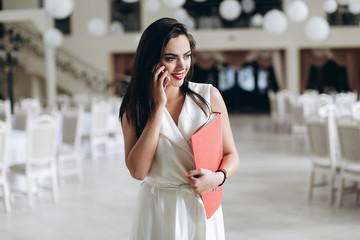 Restaurant manager. Beautifull business woman with folder restaurant menu and talk the phone.