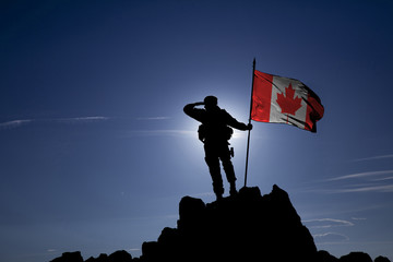Soldier on top of the mountain with the Canadian flag