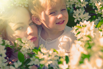 Obraz premium Happy woman and child in the blooming spring garden. Mothers day holiday concept