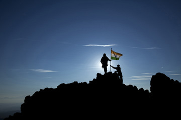 Two soldiers raise the Indian flag on a mountain top