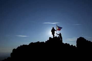 Two soldiers raise the Philippine flag on a mountain top