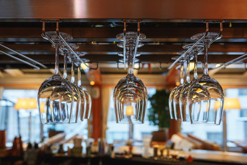 Clean wine glasses prepared by bartender and hung on the bar at a restaurant.