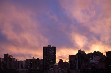 Fototapeta na wymiar Dark silhouette tops of Manhattan cityscape, bright purple-orang