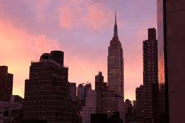 Dark silhouette tops of Manhattan cityscape, bright pink-orange