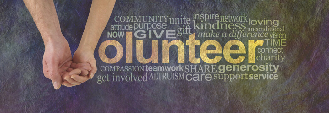 We can volunteer together - male hand cupped by a female hand making the V of VOLUNTEER surrounded by a word cloud on a rustic dark colored stone effect background