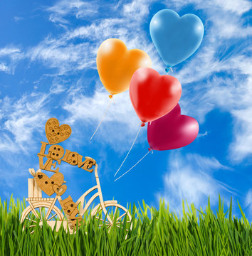 Image of decorative little man and balloons on a bicycle against the sky.