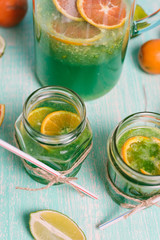 Citrus fruits. Oranges, limes and lemons. Two jar glasses of homemade lemonade on wooden table