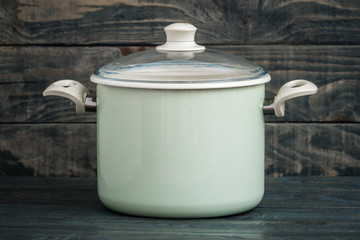 Vintage Style Green Enamel Saucepan on Blue Wooden Background