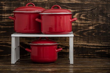 New And Clean Covered Red Saucepans on Blue Wooden Background.