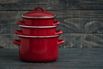 New And Clean Covered Red Saucepans on Blue Wooden Background.