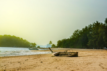 Thai traditional wooden boat on the sandy beach near the ocean. Low tide in Thailand.