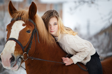 Young rider girl with long hair lying on horse neck. Friendship background