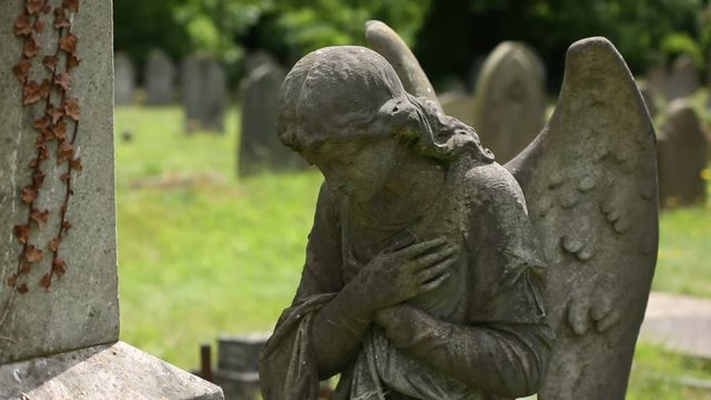Angel praying: beautiful gravestone on a cemetery