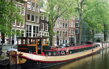 Fototapeta na wymiar Netherlands, Amsterdam. Types of cities, buildings, canals and boats. Views on the water background. Amsterdam in the spring.