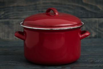 New And Clean Covered Red Saucepans on Blue Wooden Background.