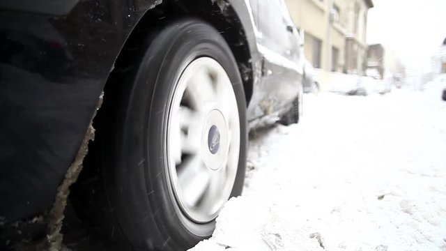 Color footage of a car's wheel being stuck in snow, and spinning.