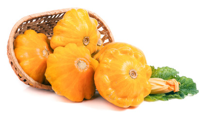 yellow pattypan squash with leaf and flower in a wicker basket isolated on white background