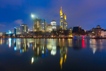 Fototapeta na wymiar Picturesque view of business district with skyscrapers and mirror reflections in the river during morning blue hour, Frankfurt am Main, Germany