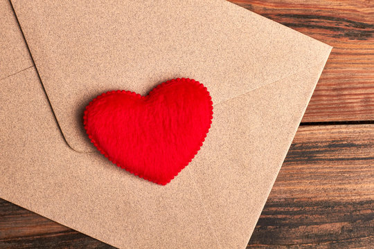 Red heart on envelope. Letter with heart on wood. Send love receive love.
