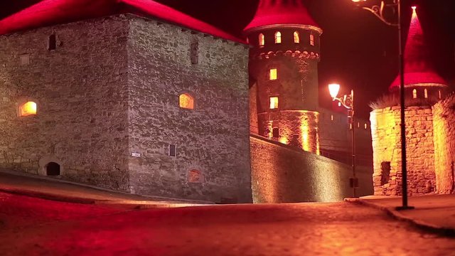 Old castle with red illumination at night, is former Ruthenian-Lithuanian castle and a later Polish fortress, located in historic city of Kamianets-Podilskyi, in historic region of Podolia in Ukraine