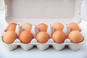 Ten dozen hen eggs in a paper container on a white background