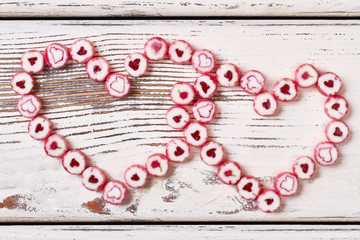 Hearts made of candies. Sweets on white wooden background. Symbol of love and relationships.
