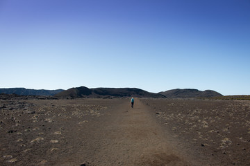 Fototapeta na wymiar Ile de la Reunion Piton de la Fournaise volcano crater rim landscape panorama woman walking a gravel road
