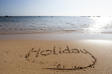 The word Holiday in sand