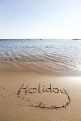 The word Holiday in sand