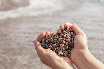 Woman hands holding stones in heart shape