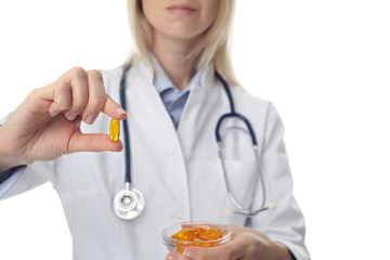 Female doctor holding with Omega 3 fish oil capsule on white background clode up.