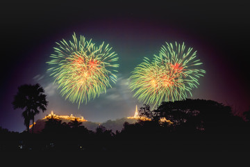 An explosion of green and red fireworks light up a Buddhist Temple on top of a hill.