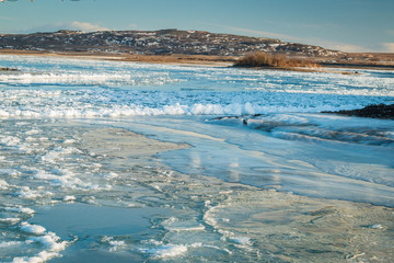 Iceland frozen river with iceblocks floating around in winter snow and ice landscape