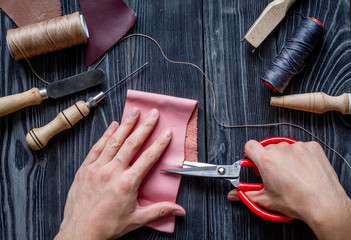 work in leather shop on dark wooden background top view