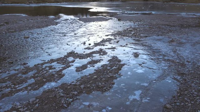Partially iced river flowing into a mountain lake