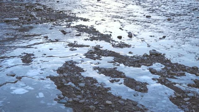 Partially iced river flowing on the rocks